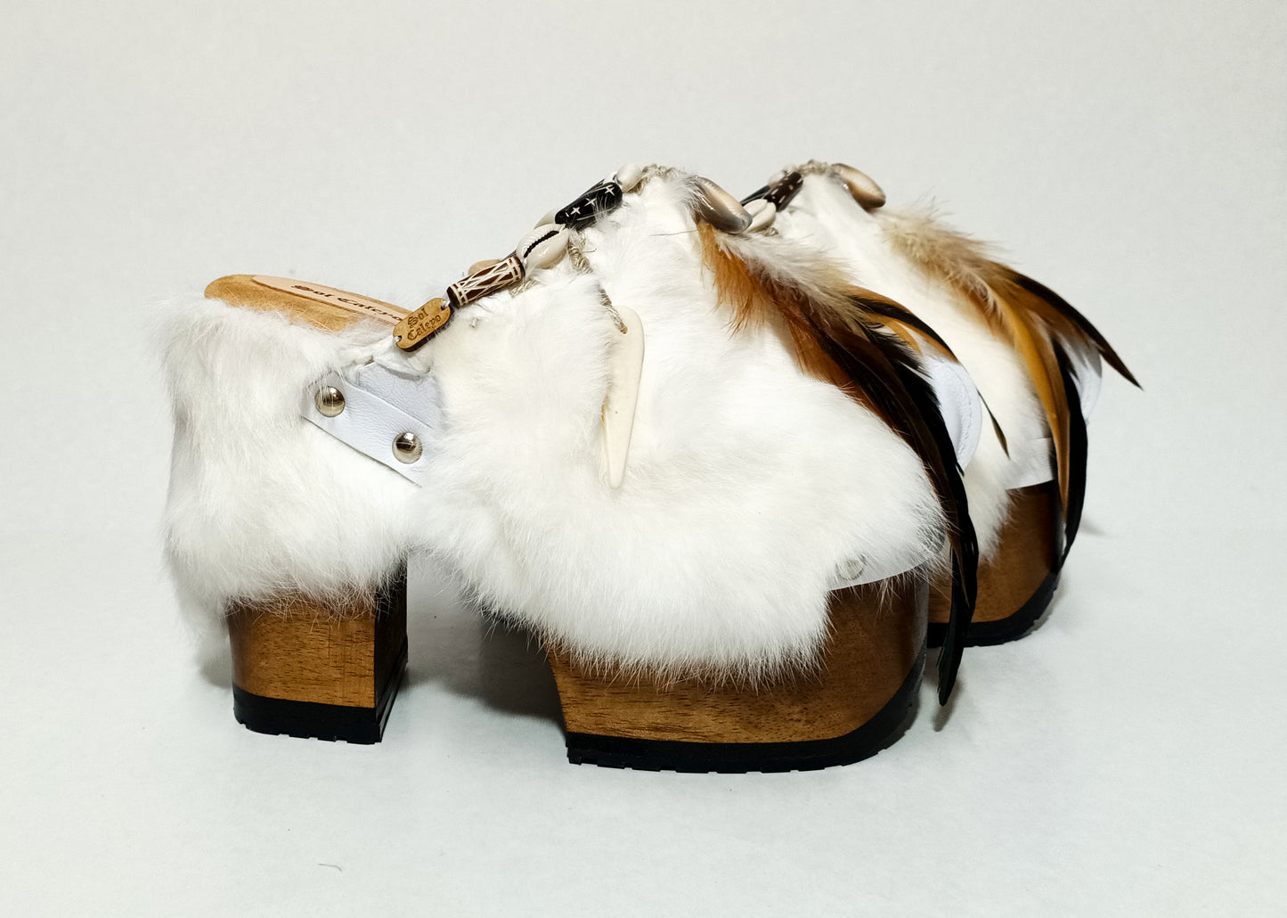 White leather and rabbit fur clogs in bohemian style, decorated with feathers, horns and natural shells. White leather mule clogs with super high heel. Sizes 34 to 47. High quality leather shoes handmade by Sol Caleyo.