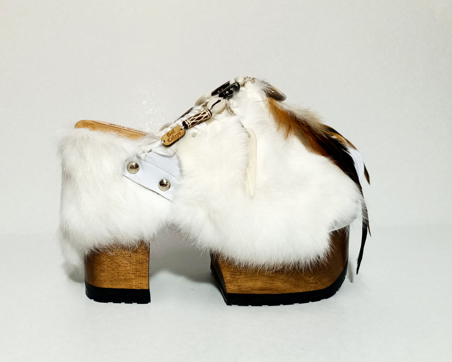 White leather and rabbit fur clogs in bohemian style, decorated with feathers, horns and natural shells. White leather mule clogs with super high heel. Sizes 34 to 47. High quality leather shoes handmade by Sol Caleyo.