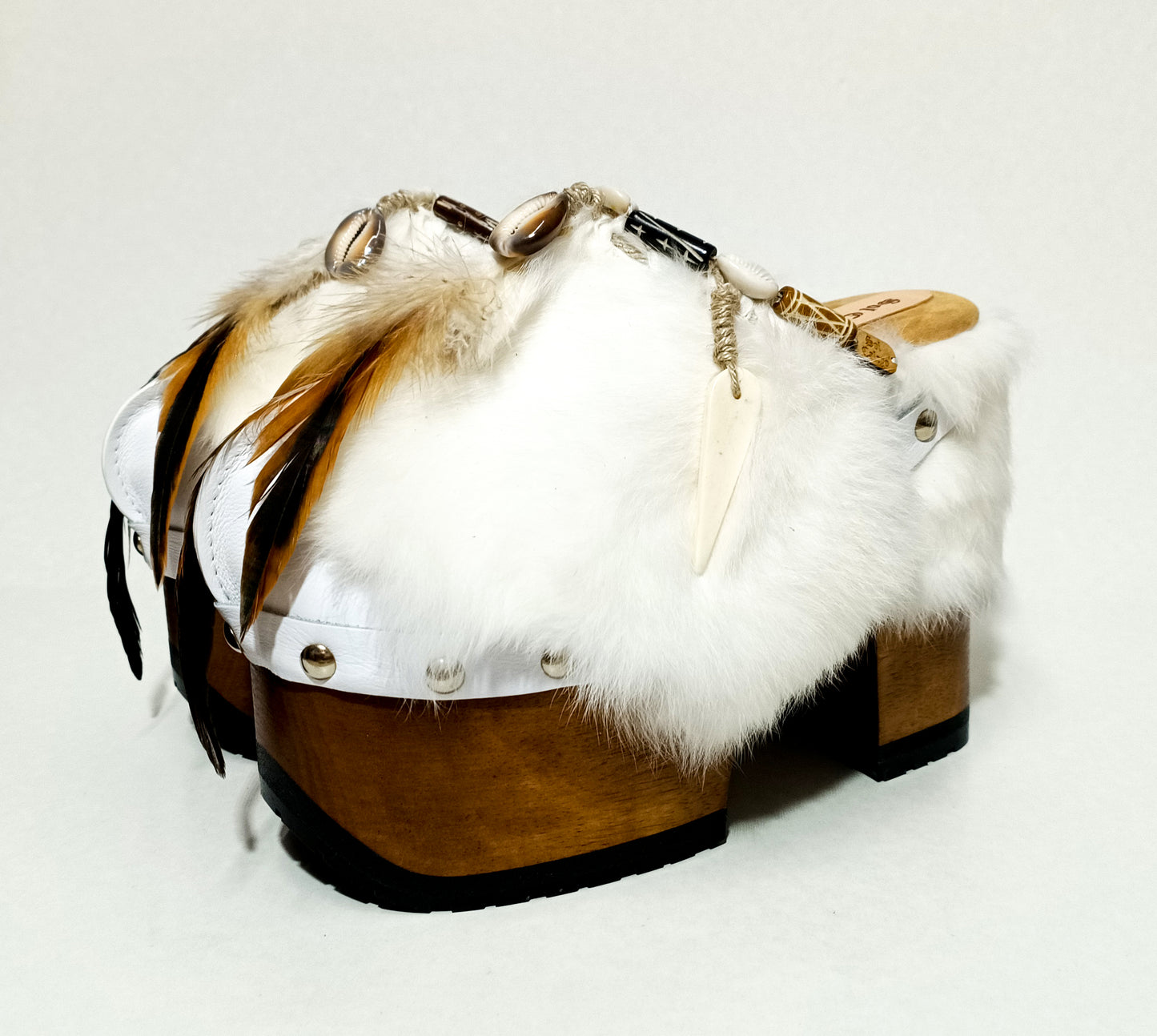 White leather and rabbit fur clogs in bohemian style, decorated with feathers, horns and natural shells. White leather mule clogs with super high heel. Sizes 34 to 47. High quality leather shoes handmade by Sol Caleyo.