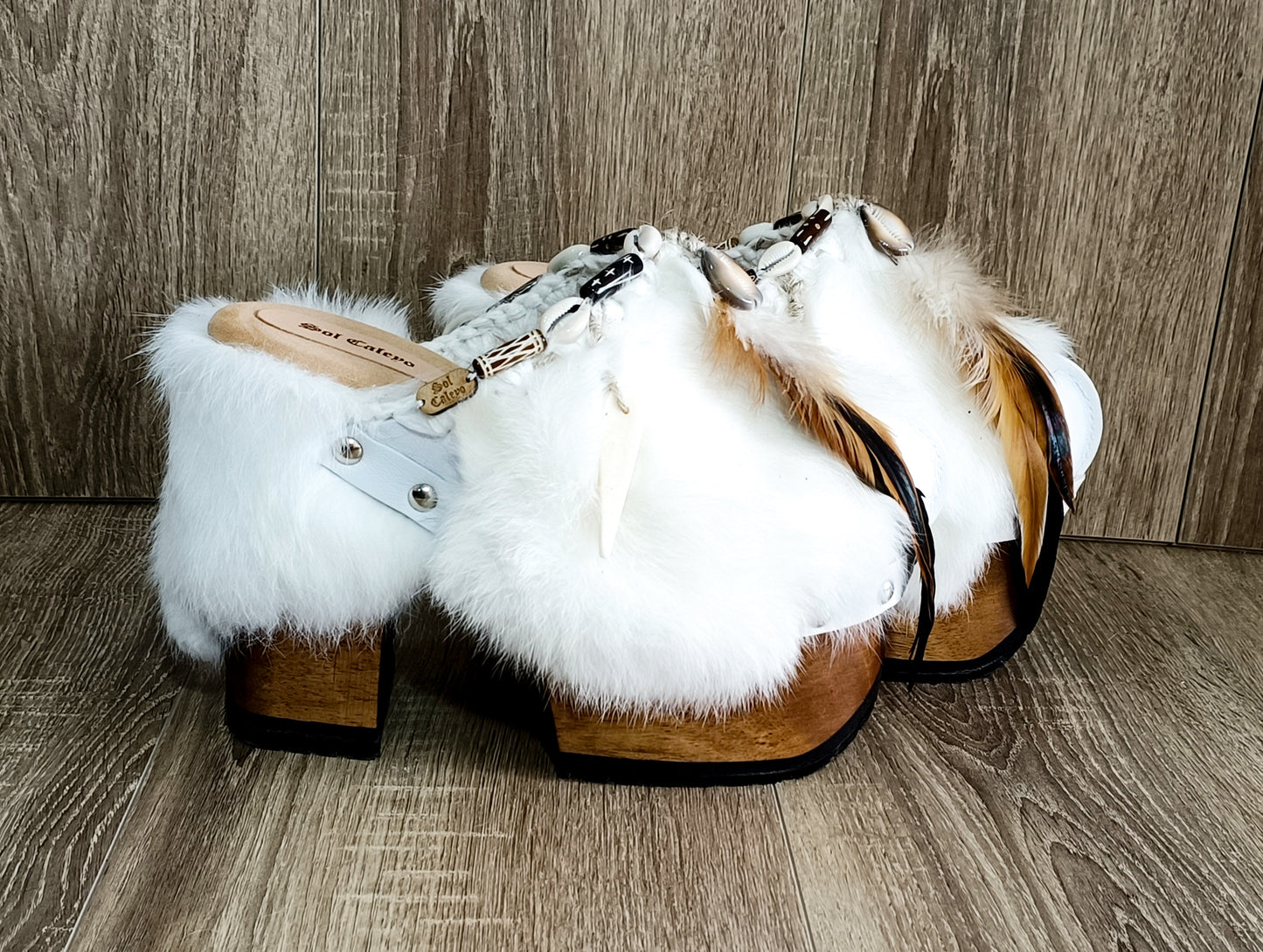 White leather and rabbit fur clogs in bohemian style, decorated with feathers, horns and natural shells. White leather mule clogs with super high heel. Sizes 34 to 47. High quality leather shoes handmade by Sol Caleyo.