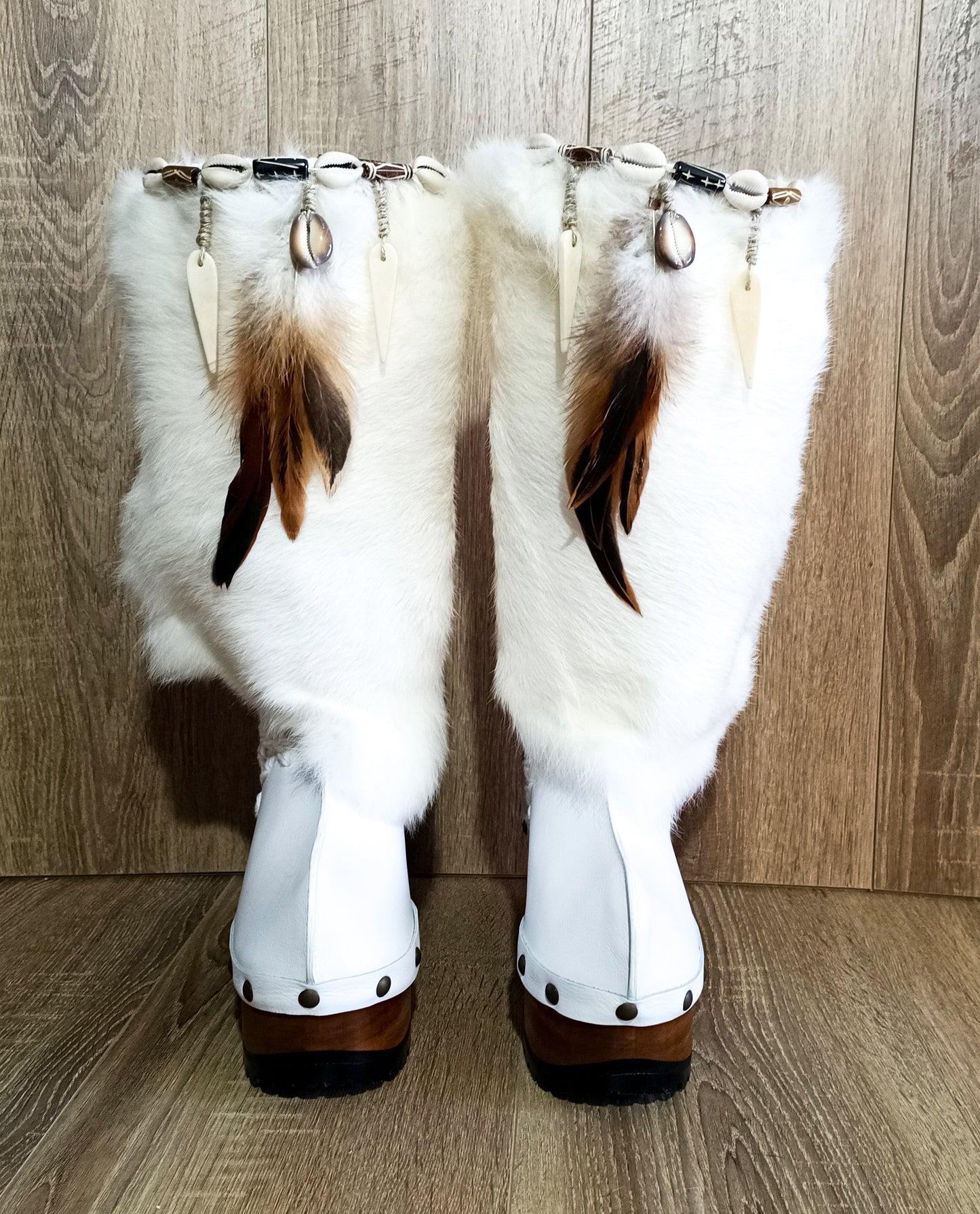 White fur boots with wooden wedge. White bohemian style leather boots. Handmade clogs shoes. White fur boots decorated with feathers, natural shells and horns. High-end handmade footwear by Sol Caleyo. Handmade Furry Shoes.
