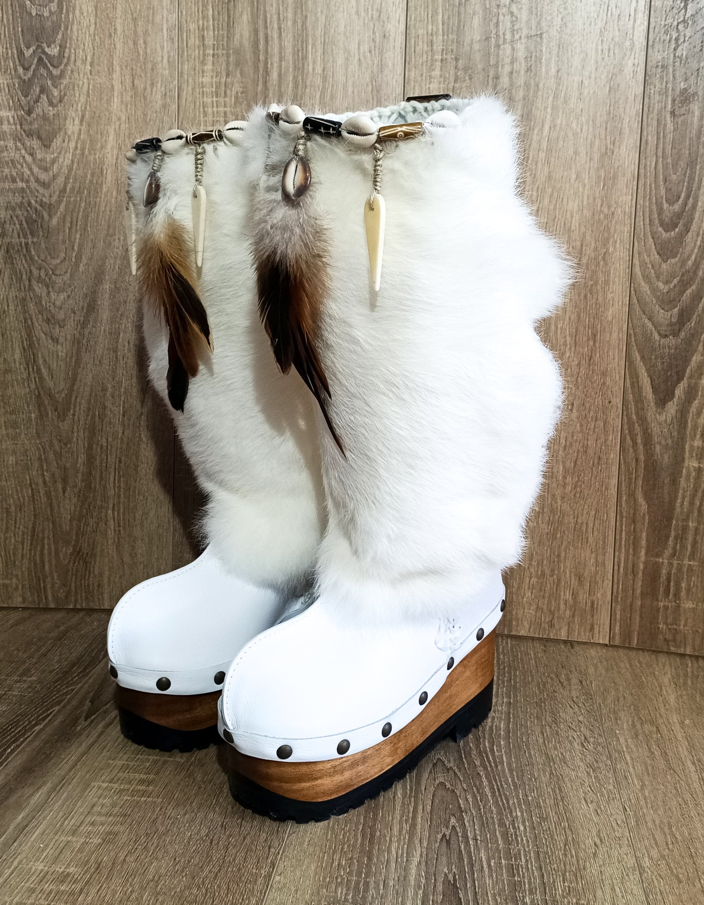 White fur boots with wooden wedge. White bohemian style leather boots. Handmade clogs shoes. White fur boots decorated with feathers, natural shells and horns. High-end handmade footwear by Sol Caleyo. Handmade Furry Shoes.