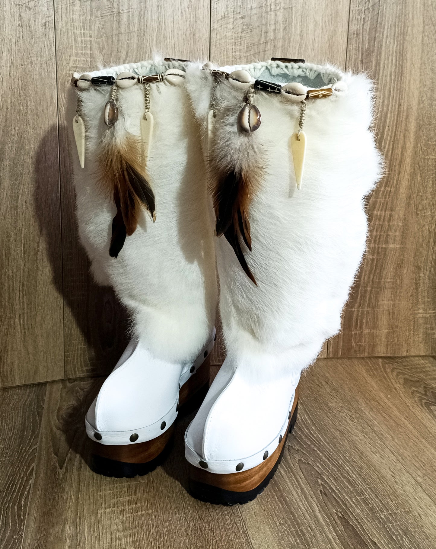 White fur boots with wooden wedge. White bohemian style leather boots. Handmade clogs shoes. White fur boots decorated with feathers, natural shells and horns. High-end handmade footwear by Sol Caleyo. Handmade Furry Shoes.