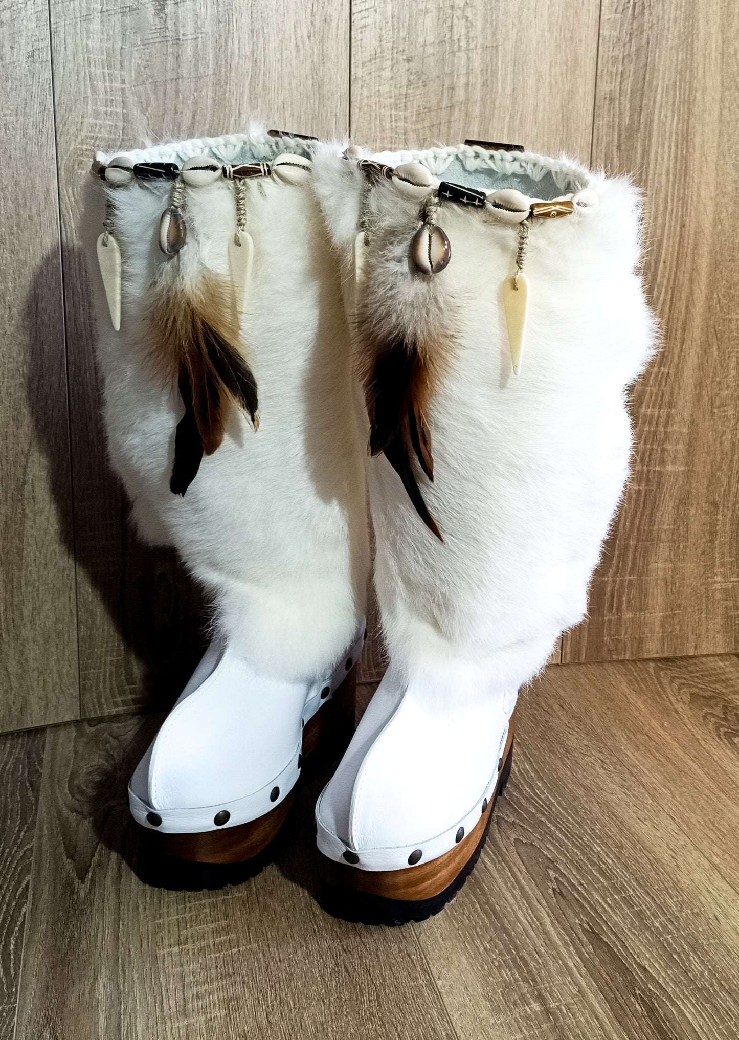 White fur boots with wooden wedge. White bohemian style leather boots. Handmade clogs shoes. White fur boots decorated with feathers, natural shells and horns. High-end handmade footwear by Sol Caleyo. Handmade Furry Shoes.