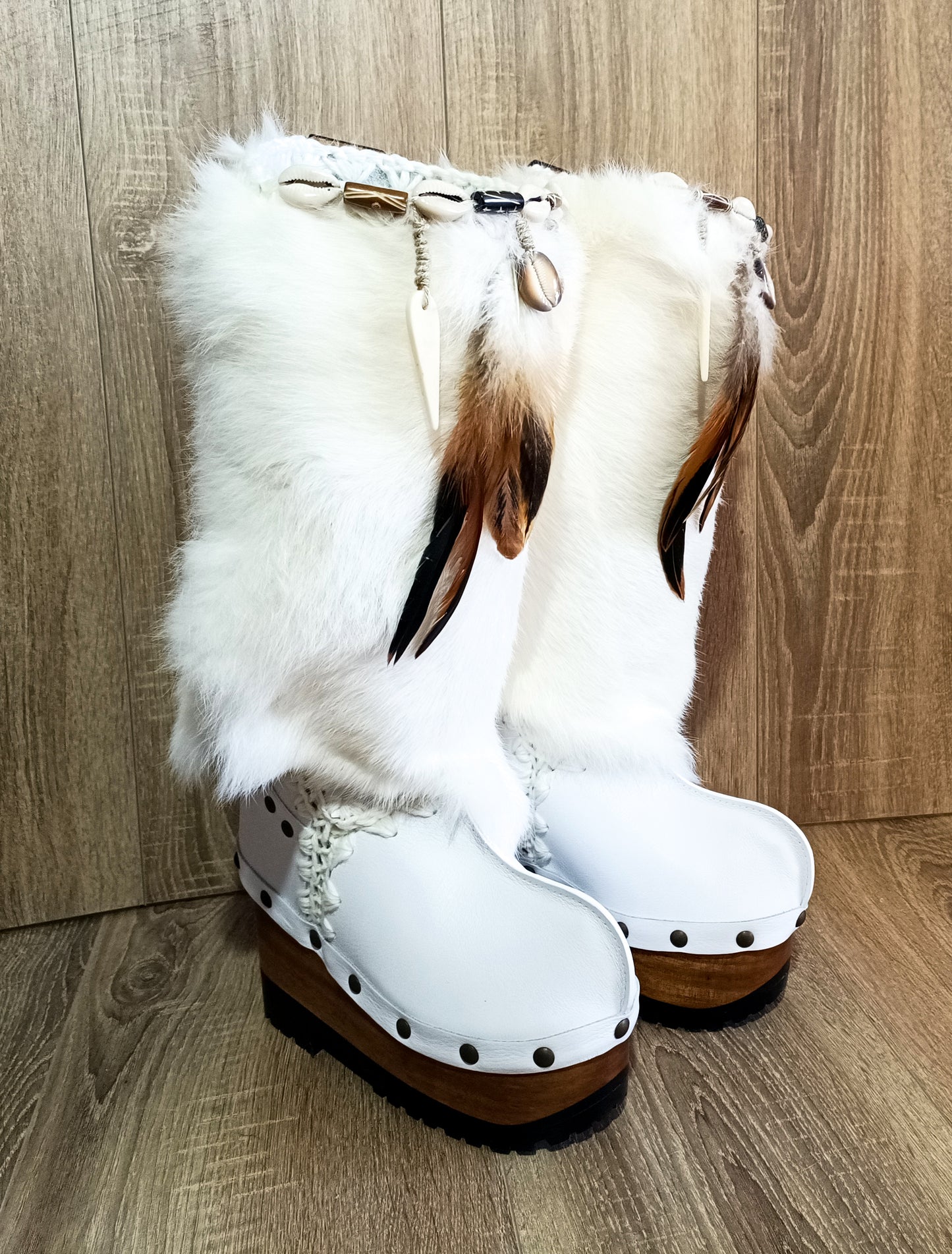 White fur boots with wooden wedge. White bohemian style leather boots. Handmade clogs shoes. White fur boots decorated with feathers, natural shells and horns. High-end handmade footwear by Sol Caleyo. Handmade Furry Shoes.