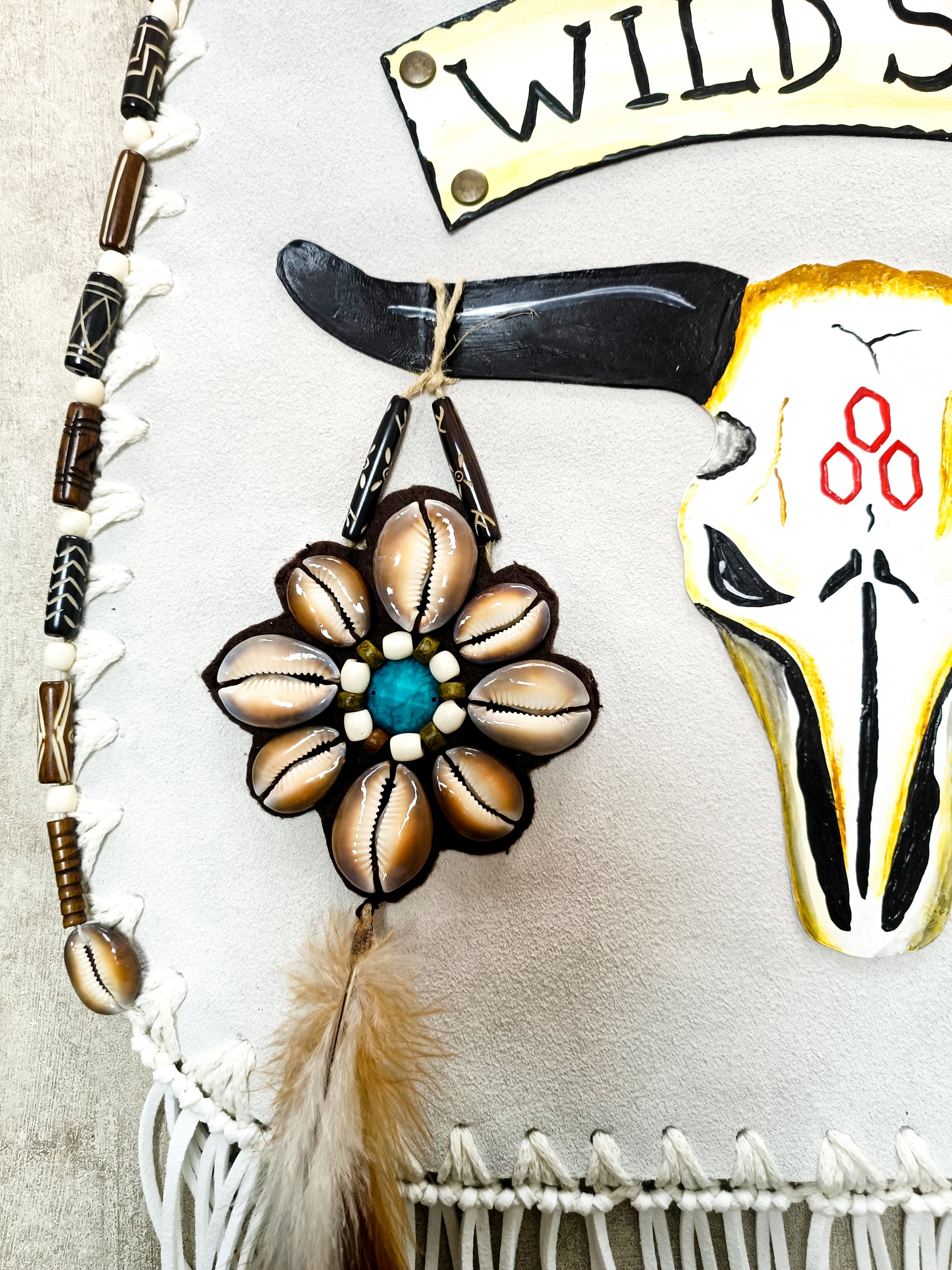 Bohemian-style white leather bag. Handmade leather bag with hand-painted buffalo decorated with shells, feathers, carved horn, and felcos. Handmade leather bag by Sol Caleyo.