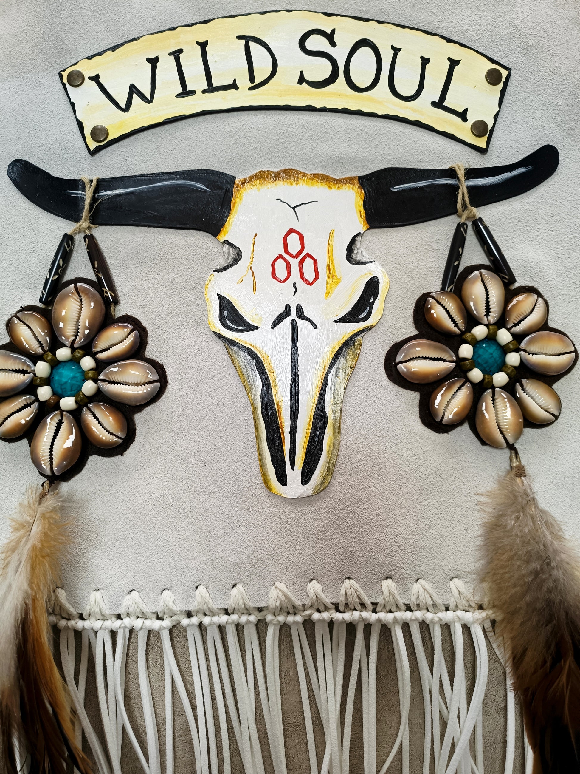 Bohemian-style white leather bag. Handmade leather bag with hand-painted buffalo decorated with shells, feathers, carved horn, and felcos. Handmade leather bag by Sol Caleyo.