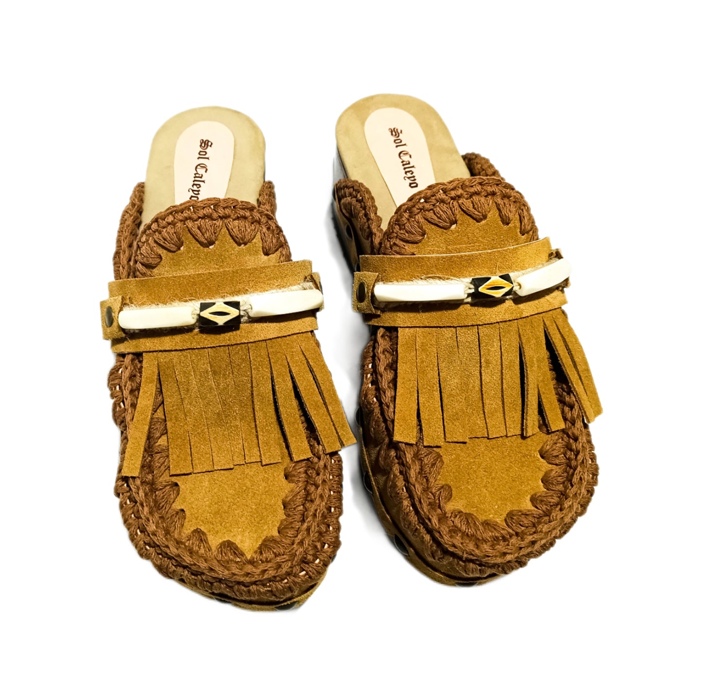 Moccasin style suede leather clogs, decorated with fringes and horns. Moccasin style leather mules. High-end footwear handmade by Sol Caleyo.