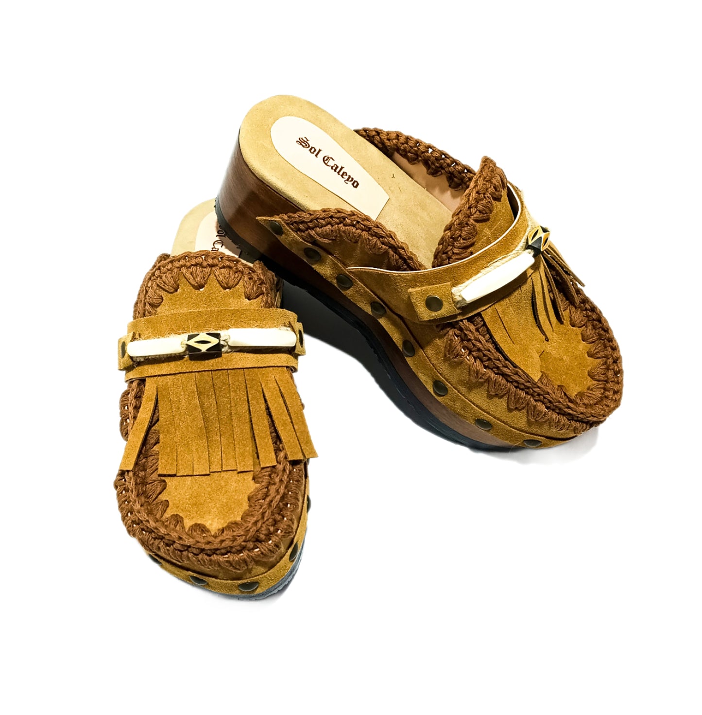 Moccasin style suede leather clogs, decorated with fringes and horns. Moccasin style leather mules. High-end footwear handmade by Sol Caleyo.
