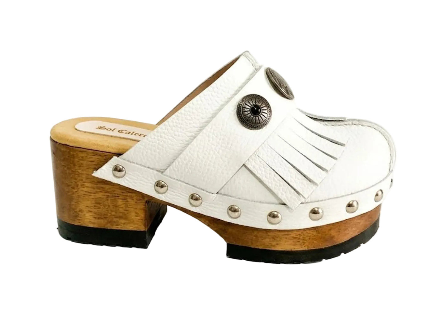 Top view of a pair of handmade white textured full-grain leather clogs with leather fringes and detailed Native American chief profile metal conchos on a wooden platform.