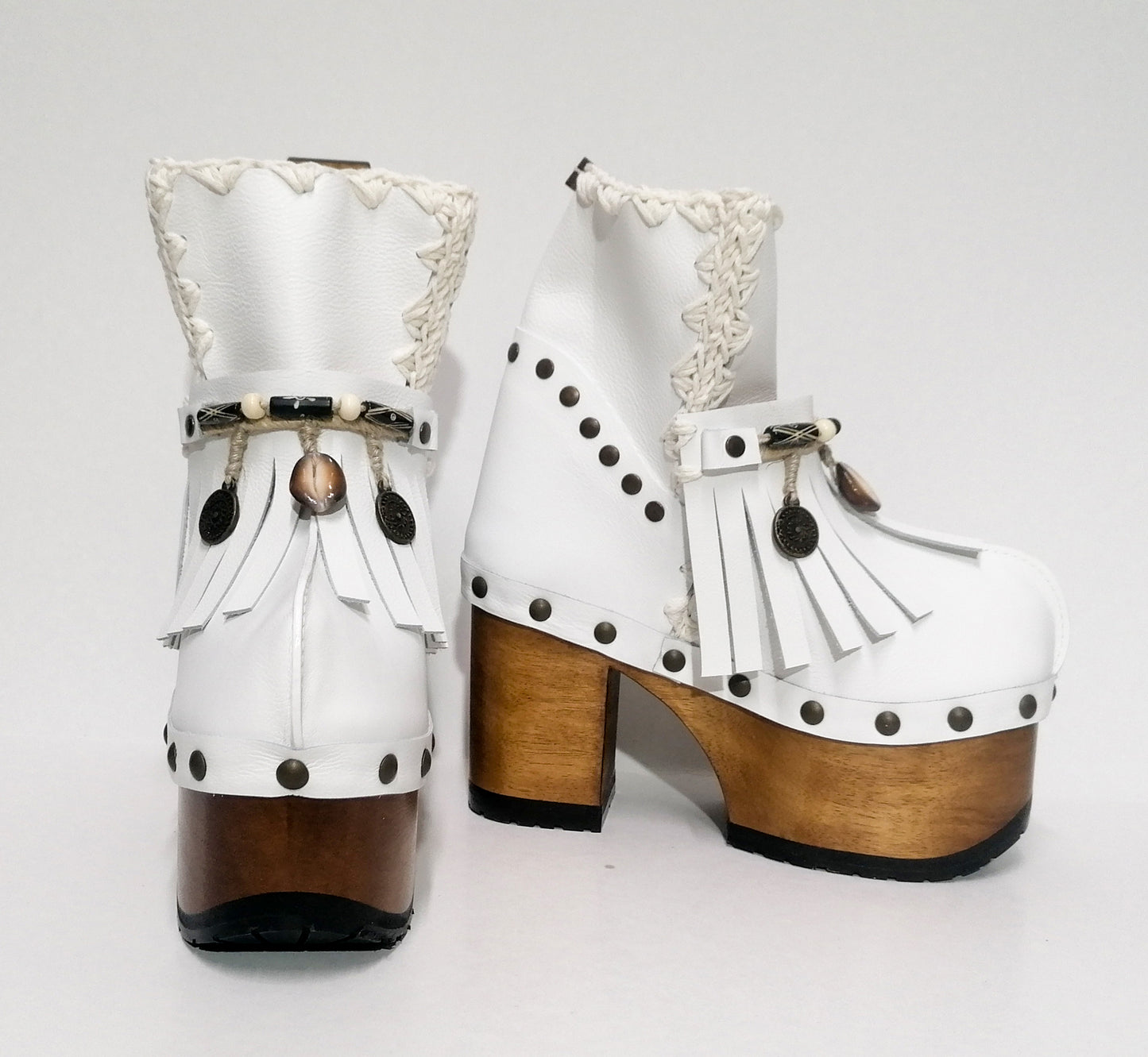 White leather clog boot. White leather boho style clog boot. White leather boot decorated with fringes, shells, coins and carved bone with a unique boho style. Super high heeled wooden boots 70's style. Sizes 34 to 47. High quality handmade leather shoes by sol Caleyo. Sustainable fashion.