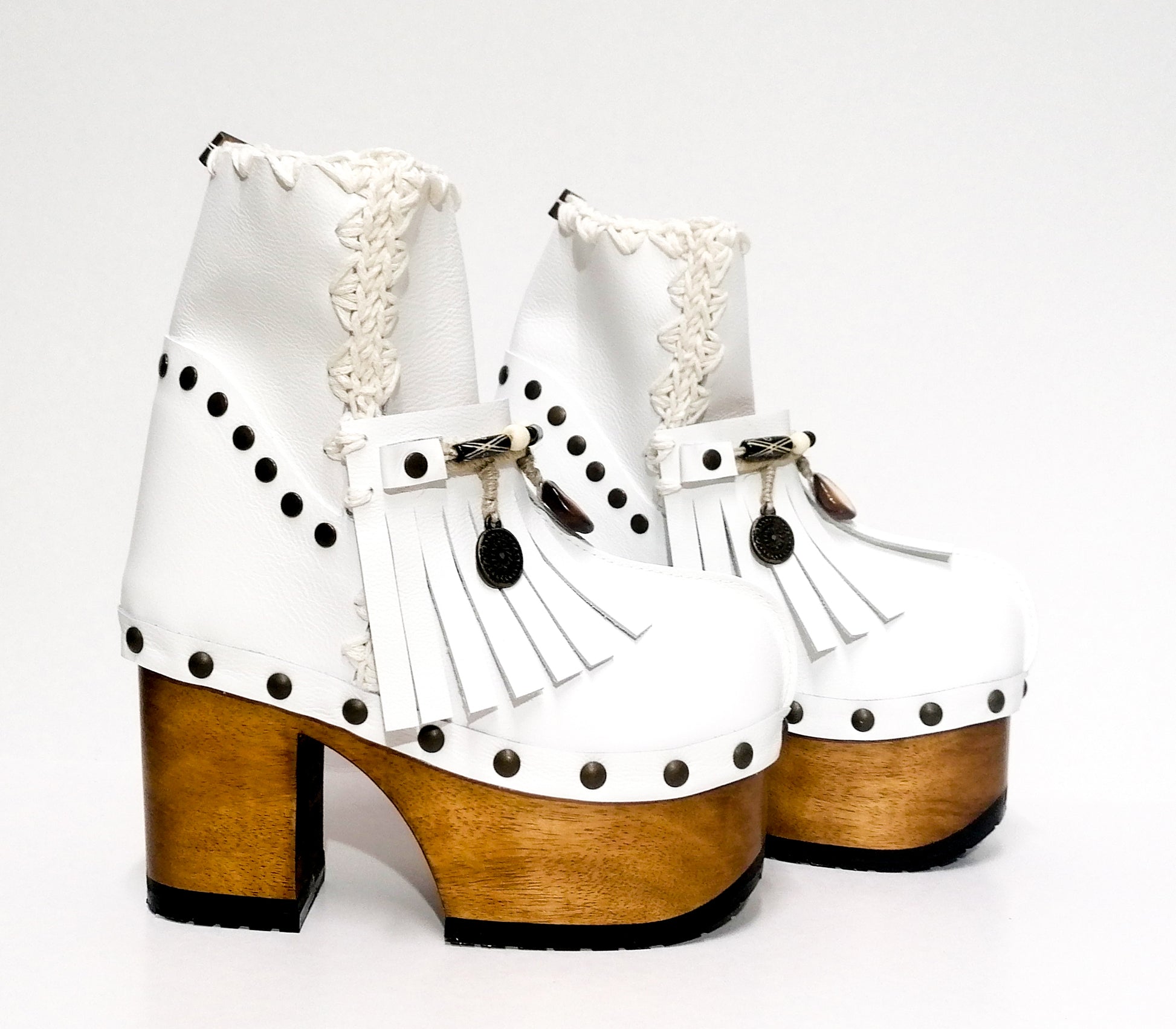 White leather clog boot. White leather boho style clog boot. White leather boot decorated with fringes, shells, coins and carved bone with a unique boho style. Super high heeled wooden boots 70's style. Sizes 34 to 47. High quality handmade leather shoes by sol Caleyo. Sustainable fashion.