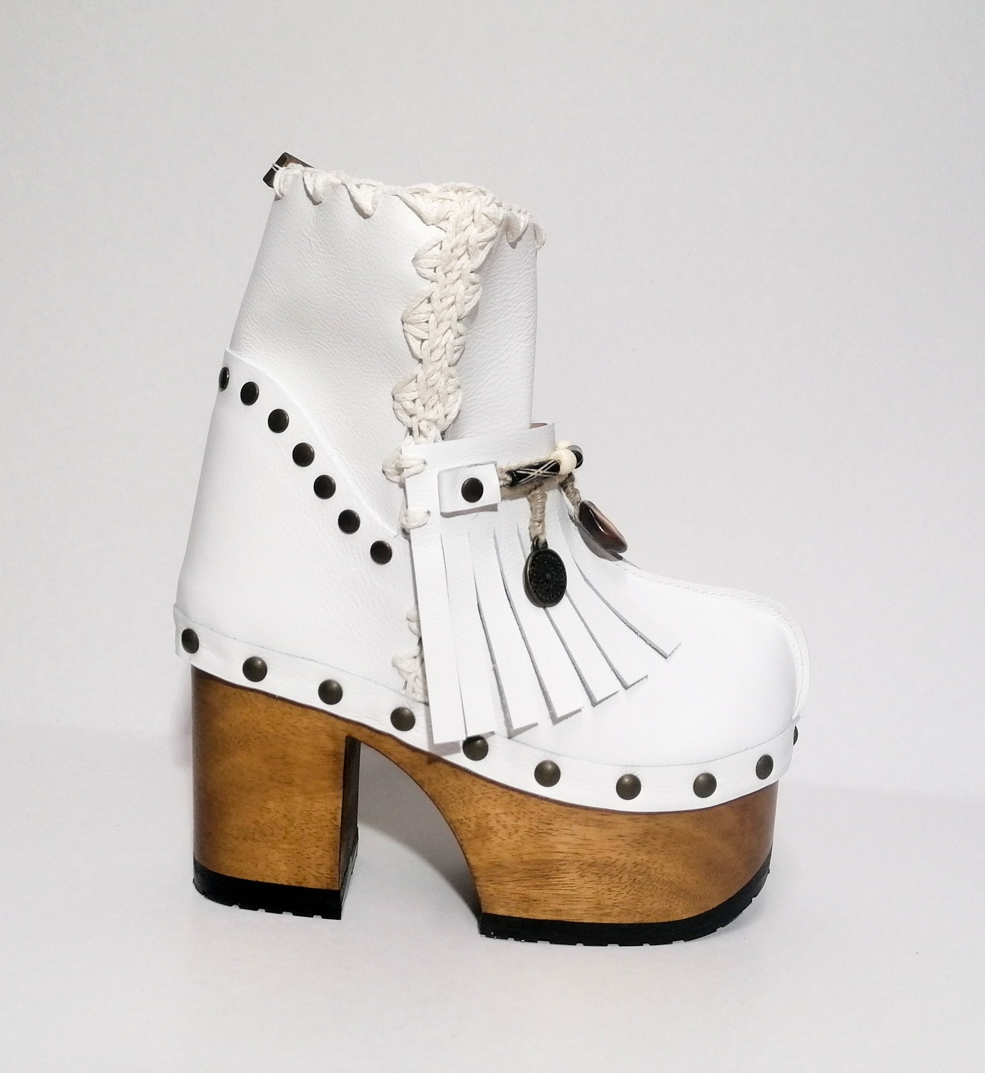 White leather clog boot. White leather boho style clog boot. White leather boot decorated with fringes, shells, coins and carved bone with a unique boho style. Super high heeled wooden boots 70's style. Sizes 34 to 47. High quality handmade leather shoes by sol Caleyo. Sustainable fashion.