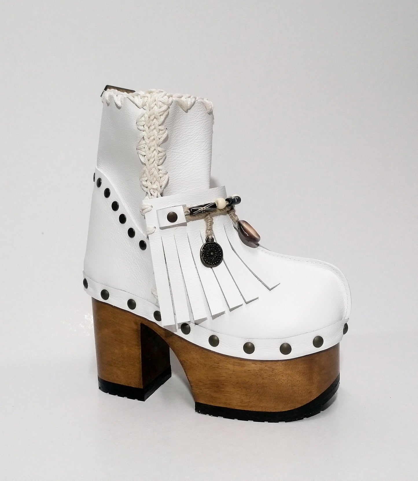 White leather clog boot. White leather boho style clog boot. White leather boot decorated with fringes, shells, coins and carved bone with a unique boho style. Super high heeled wooden boots 70's style. Sizes 34 to 47. High quality handmade leather shoes by sol Caleyo. Sustainable fashion.