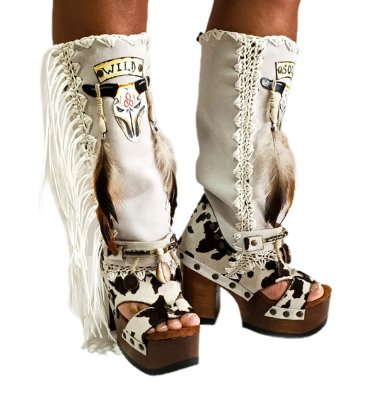 Handmade cowboy boots, white boots with cowhide and fringes. Cowboy style boots with hand painted buffalo, feathers, coins and natural shells. Vintage style platform boots. High-end leather footwear handmade by Sol Caleyo.