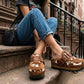Blogger wearing Oxford Clogs Cowhide Print with jeans and a vintage t-shirt, sitting on city steps for a boho-rock look.