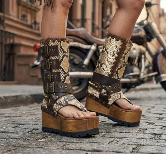 Model wearing Alabama Flip Flops Snake Boots with exotic snake-print leather, featuring a boho-chic luxury style with gold pyramid studs and high platform wedges.