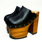 Antique-gold studs on black leather platform mule clogs, Wooden platform 17 cm heel with lacquer, Tractor rubber outsole on 10 cm platform, Suede kidskin insole.