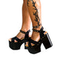 Handmade smooth black leather open toe platform sandals with crossed straps, ankle strap with old-gold pyramid studs and 13 cm wenge lacquered wooden heel by Sol Caleyo.