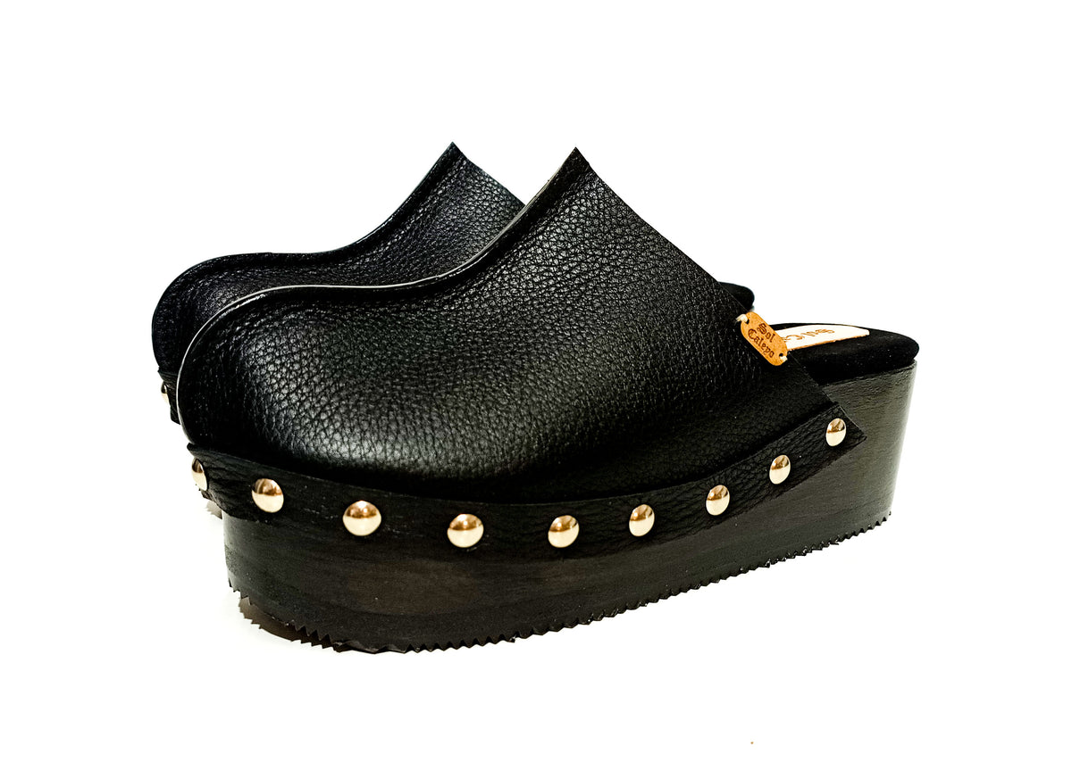 Jet black handmade leather open-back wedge mule clogs with silver studs and wooden wedge sole by Sol Caleyo.