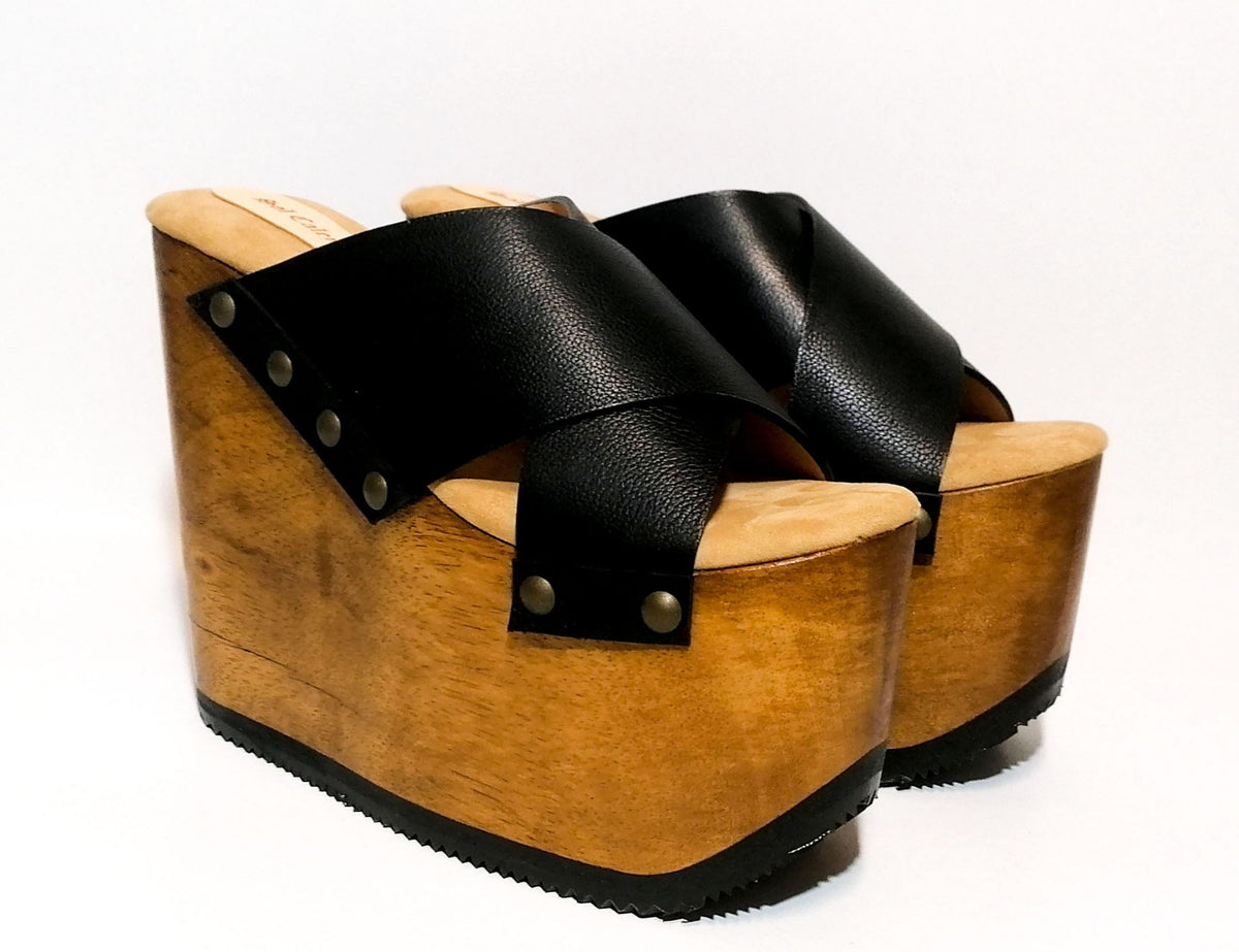 Handmade black leather wedge mule sandals with round flat old-gold studs and 15 cm natural lacquered wooden wedge by Sol Caleyo.
