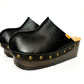 Handmade black leather open-back wedge mule clogs with old-gold studs and 6 cm wenge lacquered wooden wedge by Sol Caleyo.