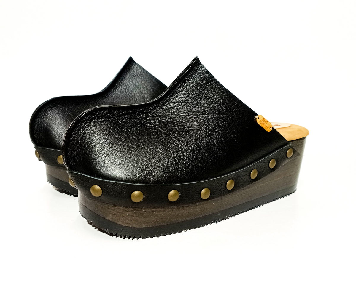 Handmade black leather open-back wedge mule clogs with old-gold studs and 6 cm wenge lacquered wooden wedge by Sol Caleyo.