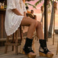 Handmade black split suede flip flop wedge boots with side fringe, crochet finish, old-gold coins, natural shells, carved bone and python print heel on a 10 cm natural lacquered wooden wedge by Sol Caleyo.