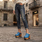 Woman wearing Blue Jeans Clogs with rolled denim jeans on cobblestone street