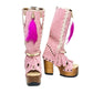 Close-up of Rhapsody Bohemia Pink Boots in premium pink suede with fringe, hand-selected feathers, and organic shells. These artisanal boho boots by Sol Caleyo feature a high hand-sculpted wooden heel and platform.