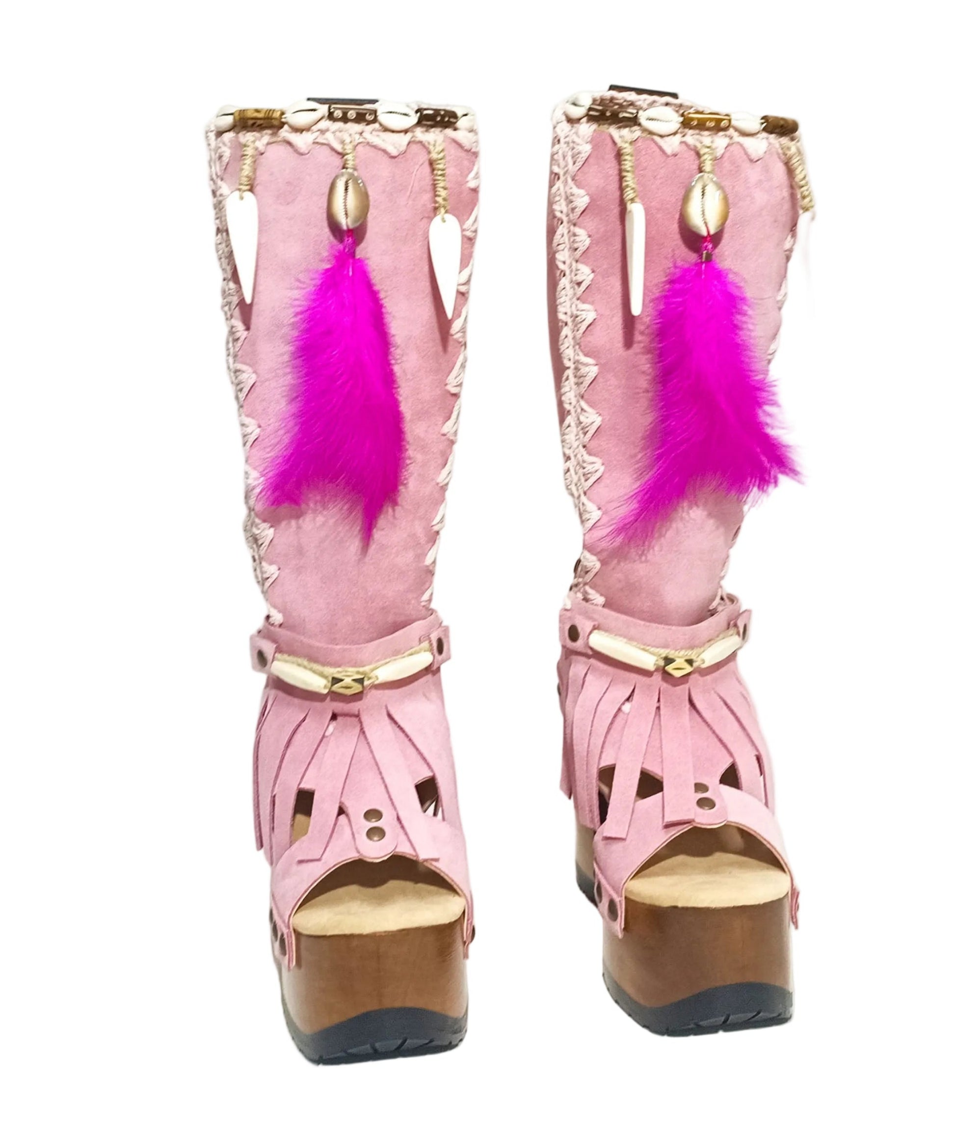 Close-up of Rhapsody Bohemia Pink Boots in premium pink suede with fringe, hand-selected feathers, and organic shells. These artisanal boho boots by Sol Caleyo feature a high hand-sculpted wooden heel and platform.