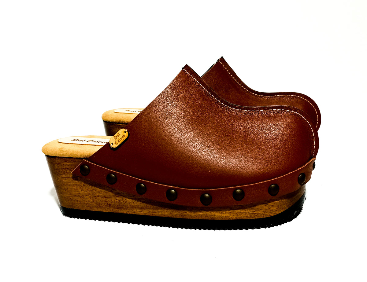 Brown handmade leather wedge mule clogs with old-gold studs and wooden wedge sole by Sol Caleyo