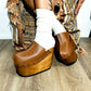 Handmade full-grain camel leather closed-toe wedge mule clogs with old-gold studs and 15 cm light natural lacquered wooden wedge by Sol Caleyo.