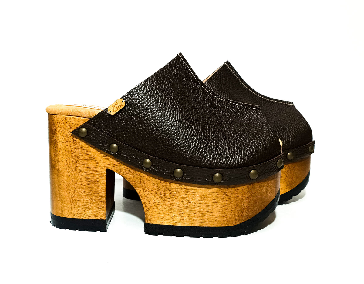 Handmade full-grain dark brown leather open toe platform mule clogs with round flat bronze studs and 12 cm natural lacquered wooden heel by Sol Caleyo.