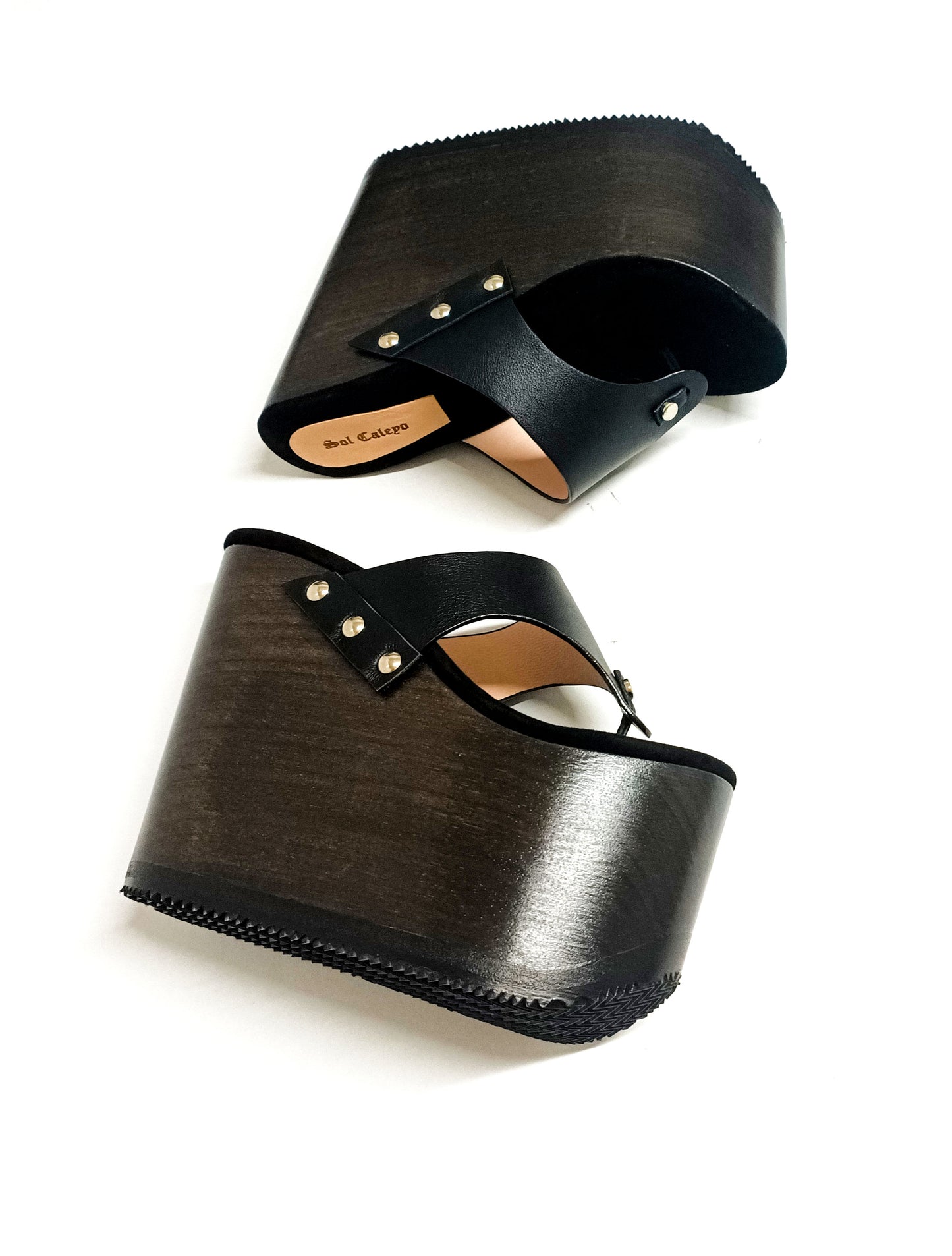 Pair of Sol Caleyo Kauai XL handcrafted flip flop sandals featuring black genuine leather straps, silver studs, and a high wengue-colored wooden platform sole.