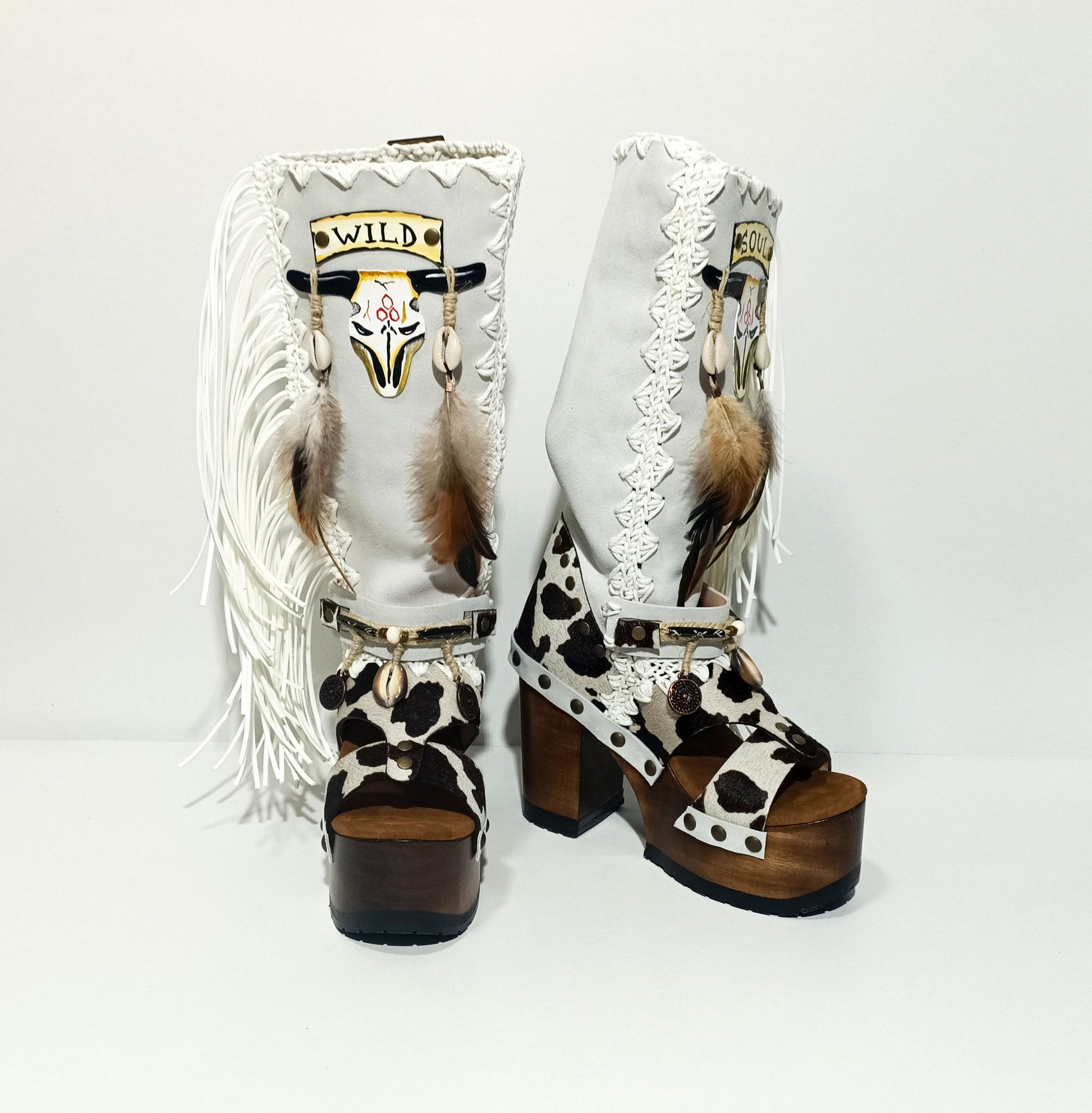 Handmade cowboy boots, white boots with cowhide and fringes. Cowboy style boots with hand painted buffalo, feathers, coins and natural shells. Vintage style platform boots. High-end leather footwear handmade by Sol Caleyo.