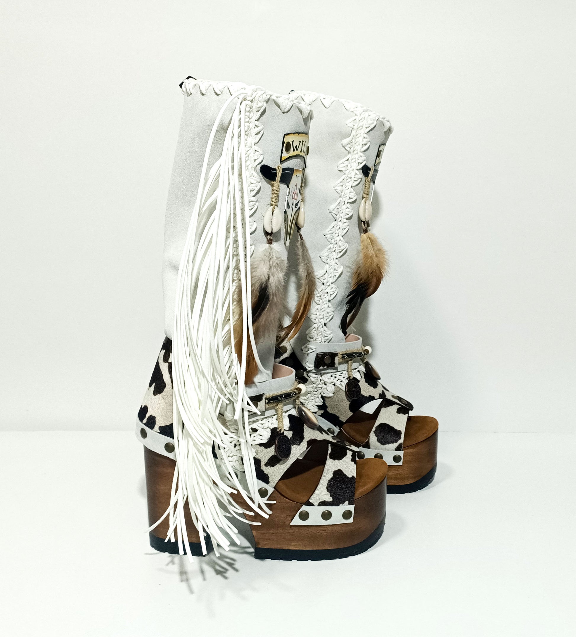 Handmade cowboy boots, white boots with cowhide and fringes. Cowboy style boots with hand painted buffalo, feathers, coins and natural shells. Vintage style platform boots. High-end leather footwear handmade by Sol Caleyo.