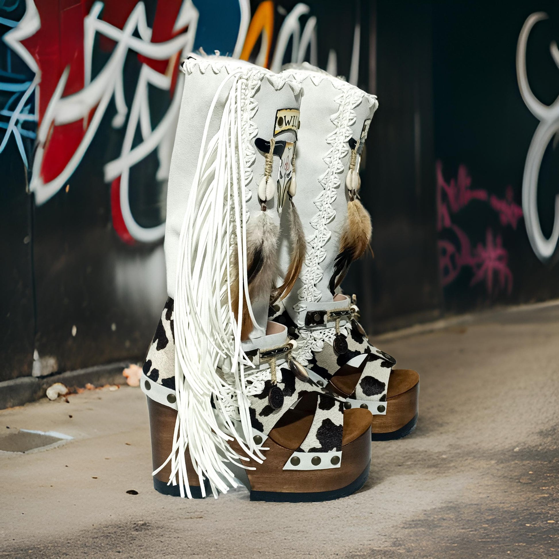 Handmade cowboy boots, white boots with cowhide and fringes. Cowboy style boots with hand painted buffalo, feathers, coins and natural shells. Vintage style platform boots. High-end leather footwear handmade by Sol Caleyo