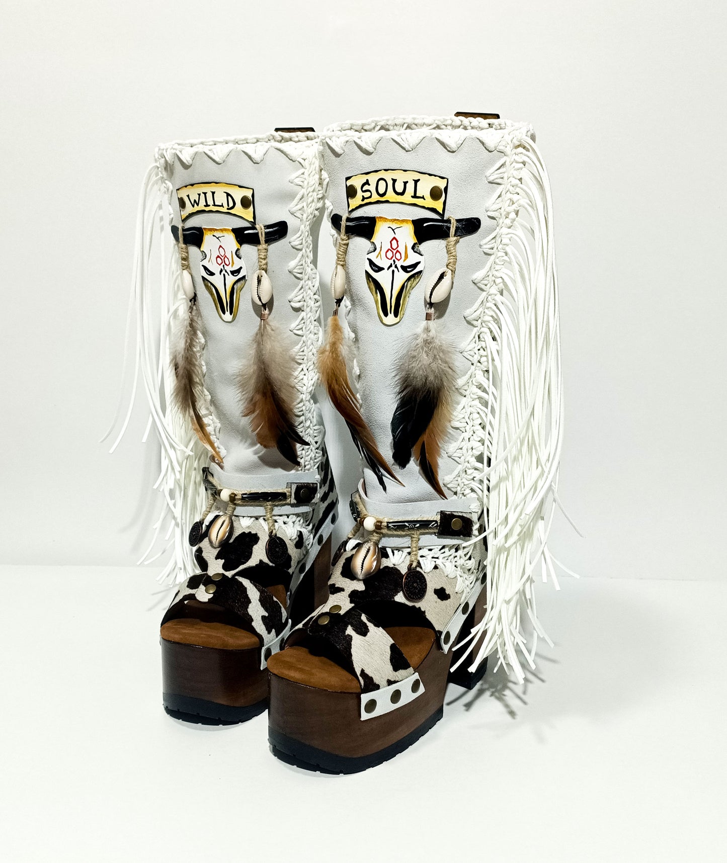 Handmade cowboy boots, white boots with cowhide and fringes. Cowboy style boots with hand painted buffalo, feathers, coins and natural shells. Vintage style platform boots. High-end leather footwear handmade by Sol Caleyo.