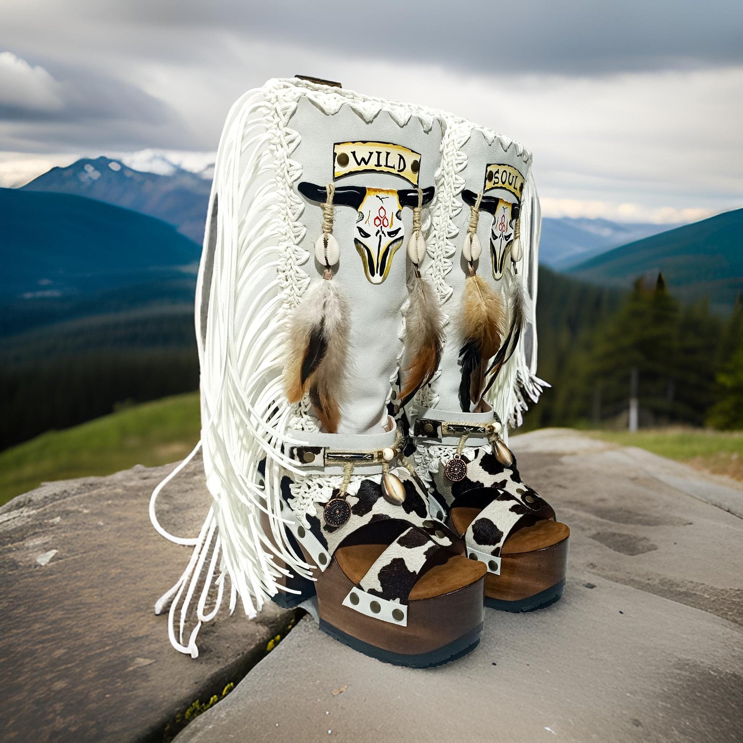 Handmade cowboy boots, white boots with cowhide and fringes. Cowboy style boots with hand painted buffalo, feathers, coins and natural shells. Vintage style platform boots. High-end leather footwear handmade by Sol Caleyo