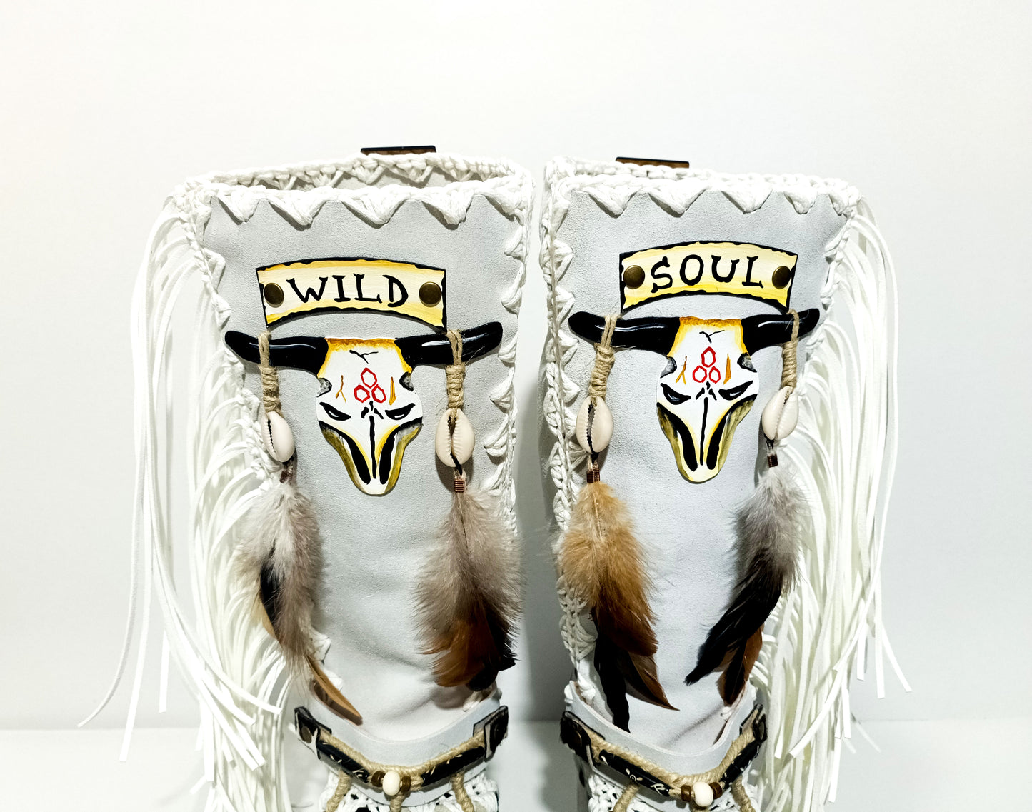 Handmade cowboy boots, white boots with cowhide and fringes. Cowboy style boots with hand painted buffalo, feathers, coins and natural shells. Vintage style platform boots. High-end leather footwear handmade by Sol Caleyo.