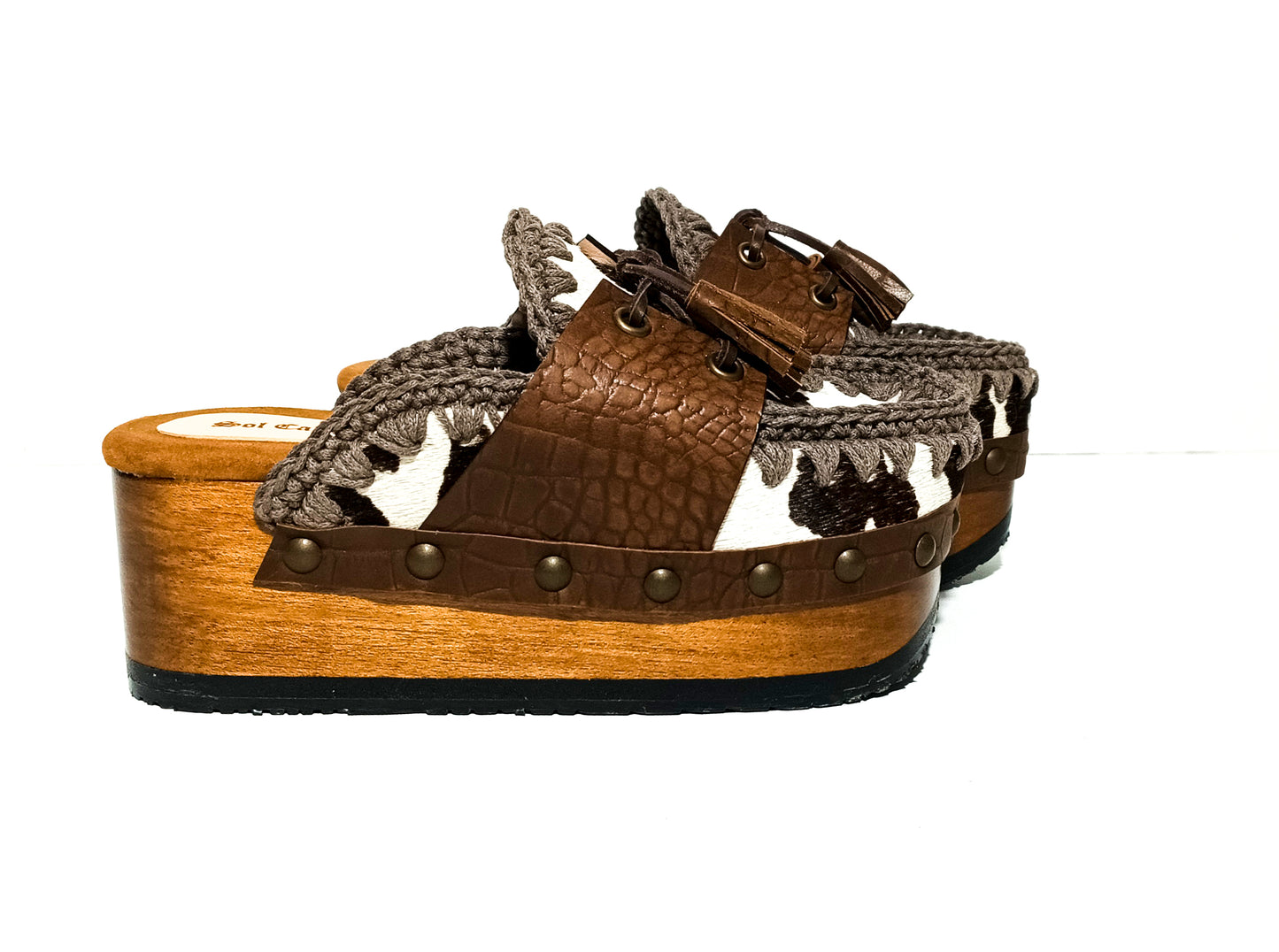 Moccasin style cowhide leather clogs, decorated with fringed laces. Moccasin style leather mules. High-end footwear handmade by Sol Caleyo.