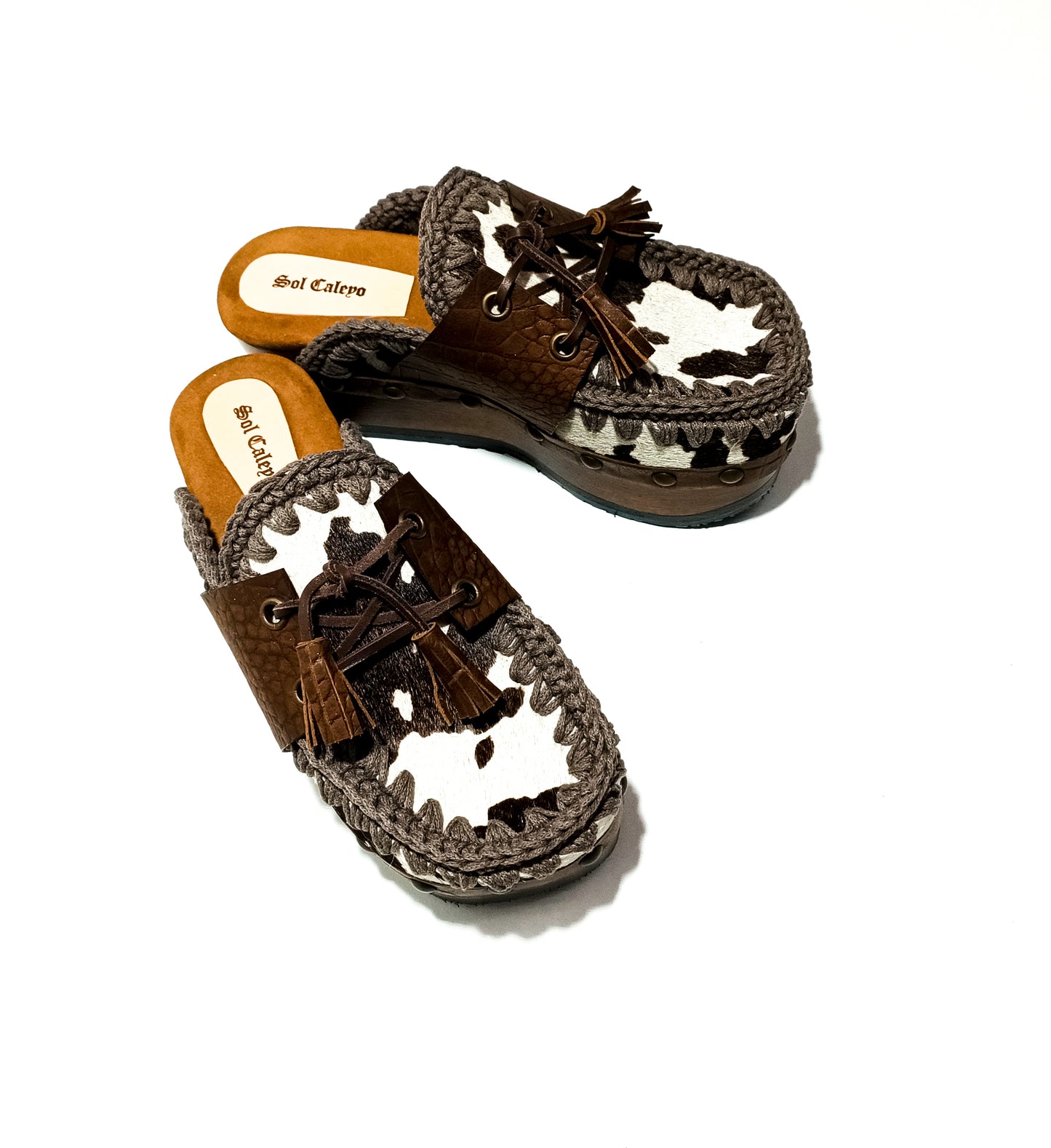 Moccasin style cowhide leather clogs, decorated with fringed laces. Moccasin style leather mules. High-end footwear handmade by Sol Caleyo.