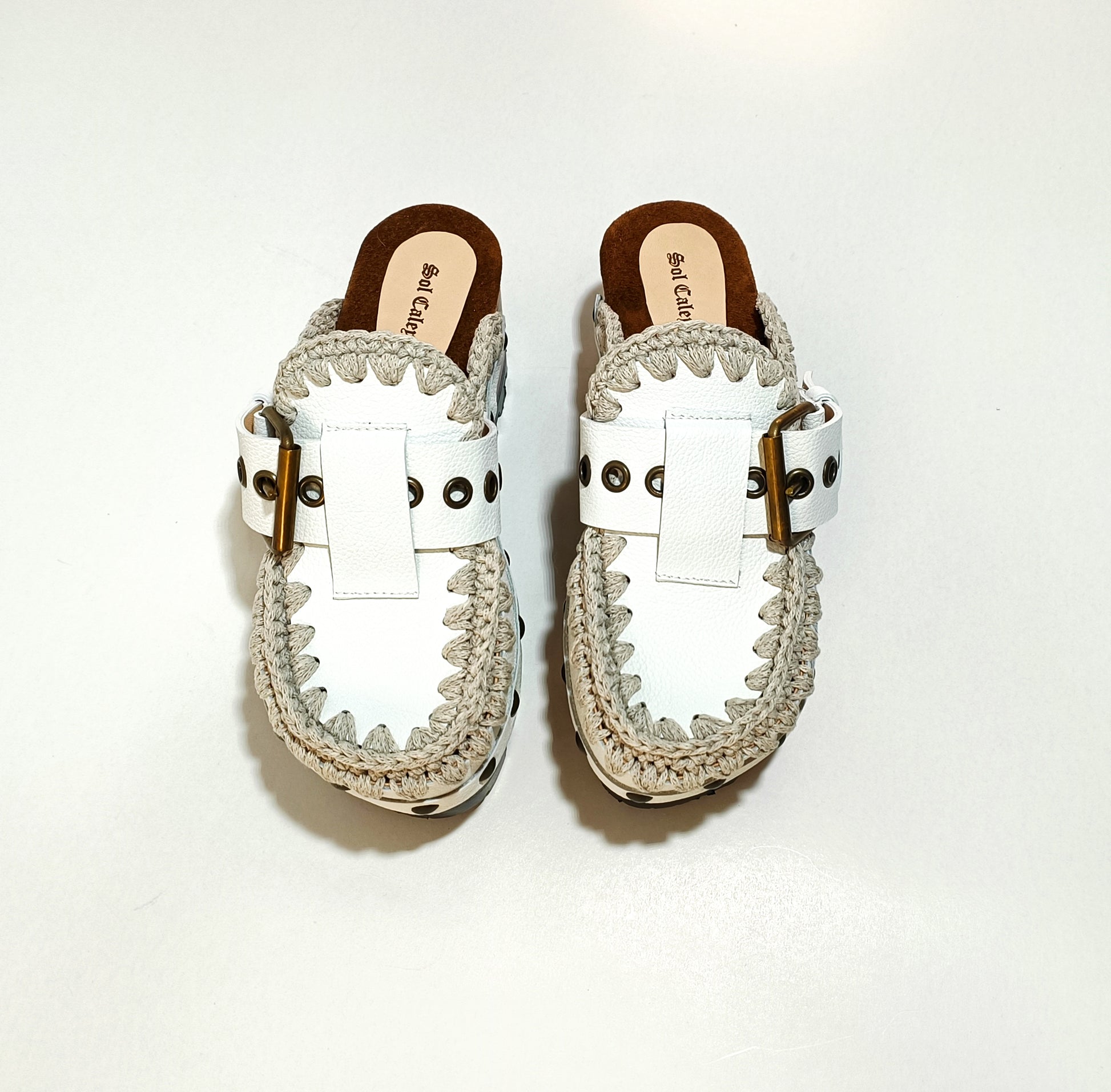 White wooden wedge clogs. White leather mules. Oxford style buckle clogs. High quality handmade shoes by Sol Caleyo.