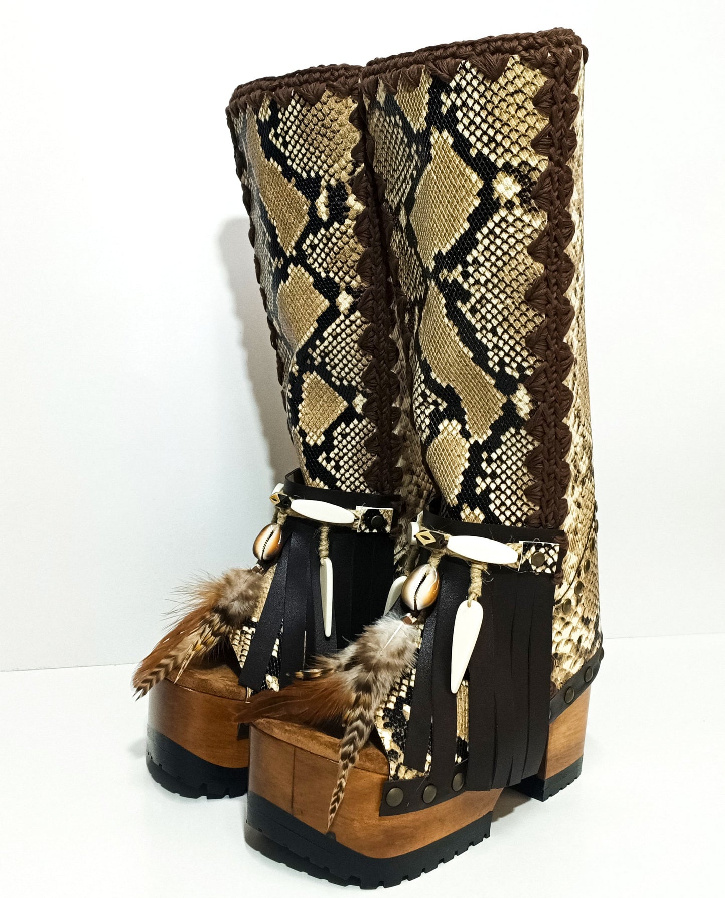 Detail of boho embellishments on handmade snake leather boots including feathers, shells and carved horn