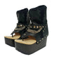 Sol Caleyo Texas Boots: Handcrafted black leather platform flip-flop sandals with wooden wedge heel, silver pyramid studs, and decorative chains. 9cm heel with zig-zag rubber traction sole.