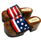 American Sandals XS by Sol Caleyo: close-up of handmade wooden platform sandals with USA flag leather strap and studs.