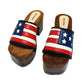 American Sandals XS by Sol Caleyo: close-up of handmade wooden platform sandals with USA flag leather strap and studs.