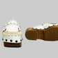Handmade Niza Moccasin Clogs in white leather with beige crochet trim, leather fringes, and bronze studs on a wooden platform with a beige tractor sole.