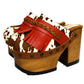 Verona Clogs by Sol Caleyo featuring light brown cow hair leather, red fringe details, and old gold studs on a high wooden platform sole with tractor grip.